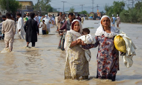 Women wade through flood waters with their children while evacuating from Nowshera Pakistan