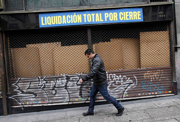 Week in Business: A man walks past a closed store reading 