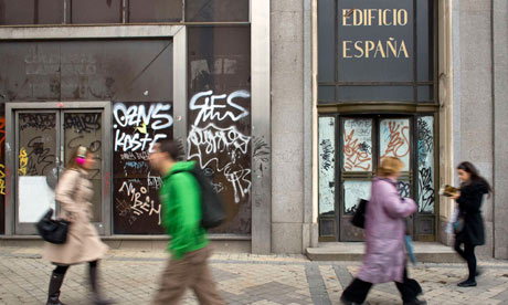 Pedestrians walk past a vacant office building in downtown Madri