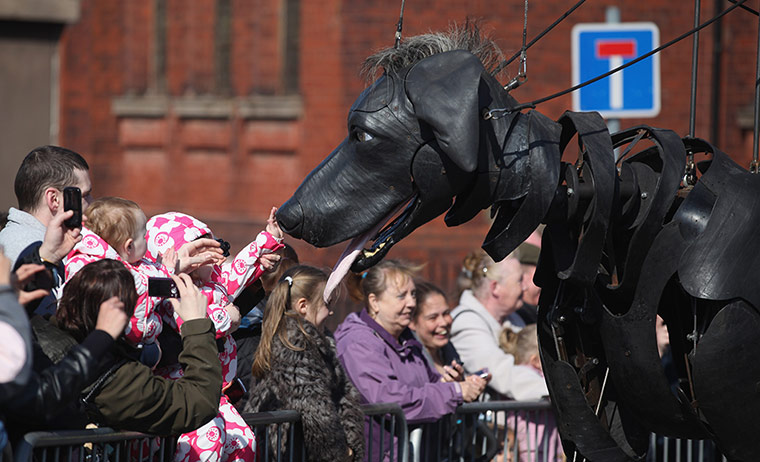 Liverpool Royal de Luxe: A little girl pats the giant pet dog of the Little Girl Giant Marionette