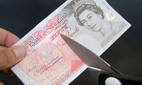 Fifty pound note being cut with scissors