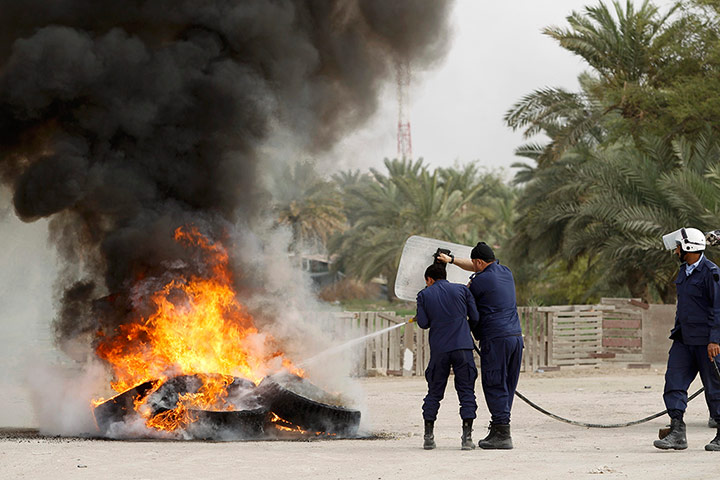 formula one: Riot police extinguish a fire during riots in Manama