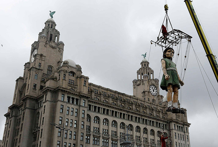 Liverpool Puppets: A giant puppet of a girl is lifted into position outside the Liver Building