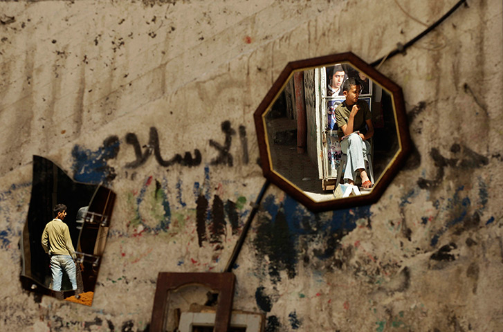 24 hours: Gaza City: Palestinians are reflected in mirrors outside their store 