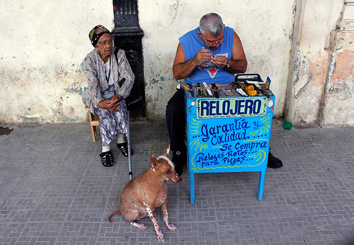 24 hours: Havana, Cuba: A privately licensed watchmaker with works at his stall 