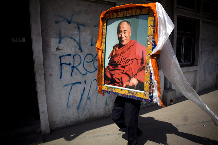 24 hours: Kathmandu, Nepal: An exiled Tibetan holds a portrait of the Dalai Lama