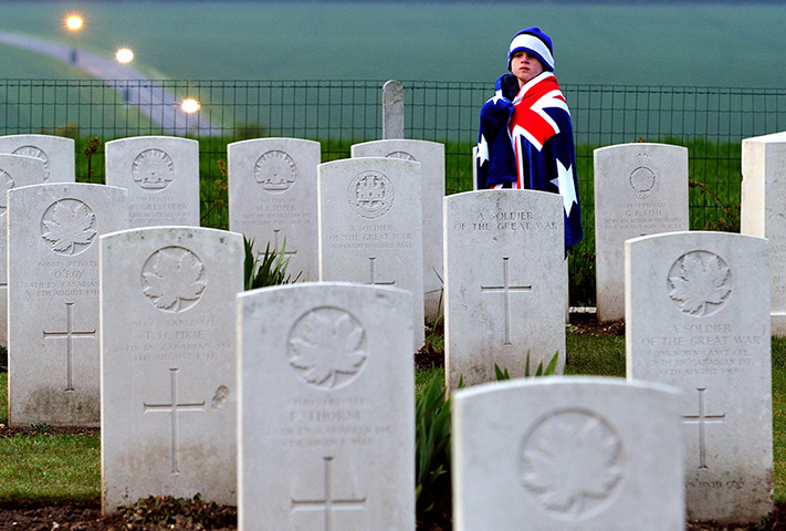 Anzac Day: A child wearing an Australian flag walks past graves in Villers-Bretonneux