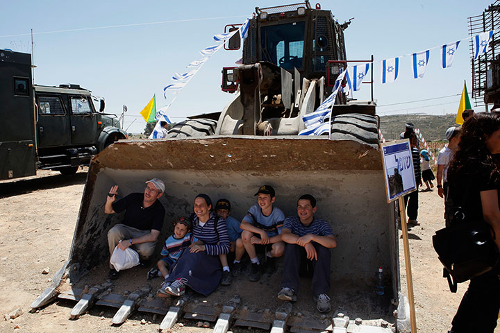 Picture Desk Live: An Israeli family poses for a picture as they sit on a military bulldozer