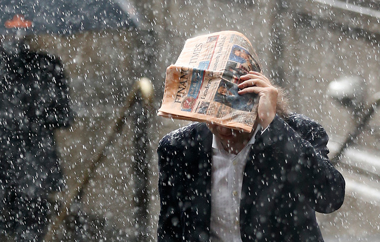 Week in Business: A man tries to shelter under a Financial Times newspaper in the rain