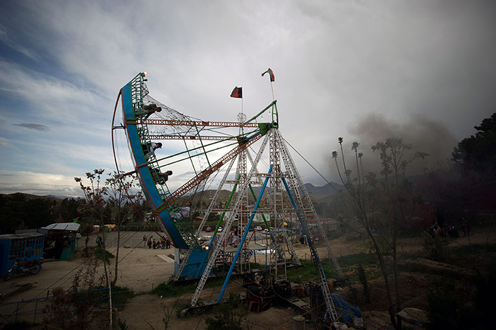 24 Hours: Afghans sit on a fairground boat swing ride in Band-e-Qargha Gulestan Park