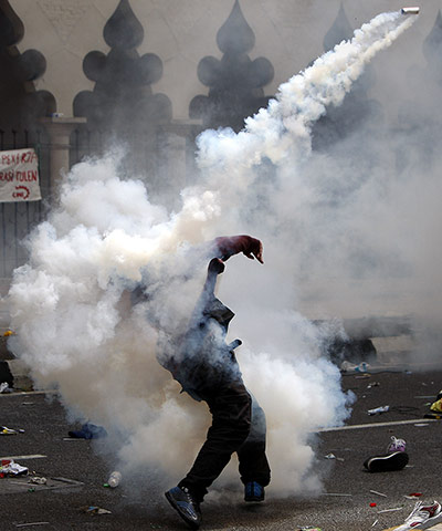 24 Hours: A protester throws back a tear gas canister fired by police in Kuala Lumpur