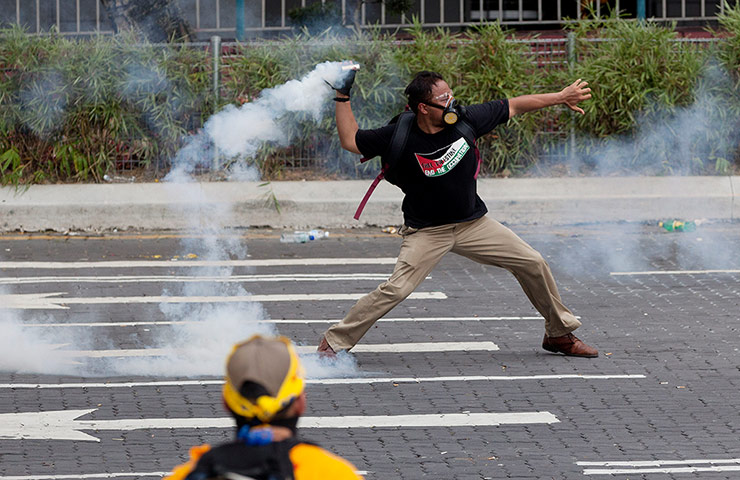 Kuala Lumpur: A protester throws a tear gas canister back at police
