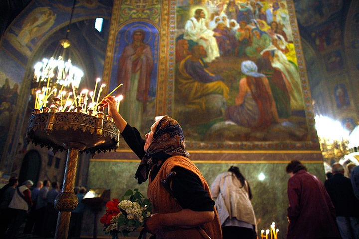 24 hours: Sofia, Bulgaria: A worshipper lights a candle as she attends Sunday mass