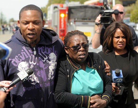 Oakland shootings: A woman in nursing attire is comforted near Oikos Universit