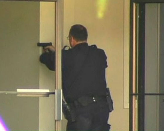 Oakland shootings: A police officer aims his pistol inside a building at Oikos University
