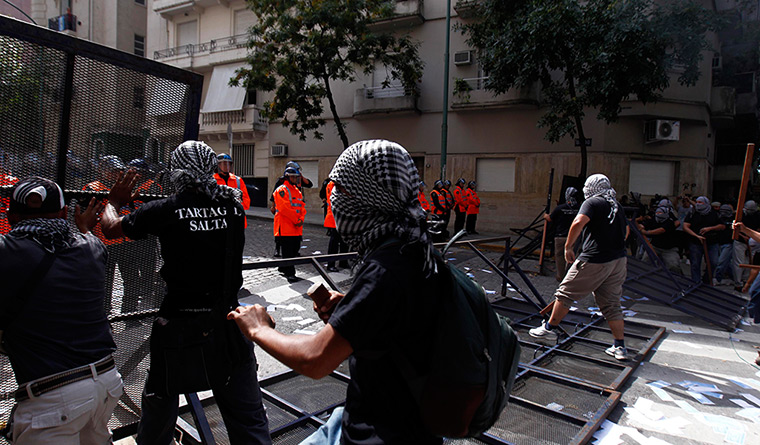 Falklands protests: Masked protesters tear down a police fence during a demonstration