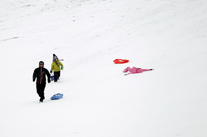 Snow returns: Members of the public go sledging on a hillside in Braemar