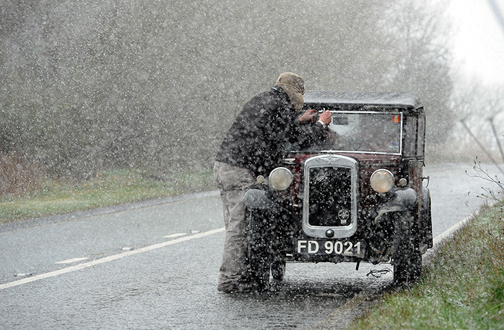 UK snow: A man tries to fix his windscreen wiper in a blizard in Corbridge