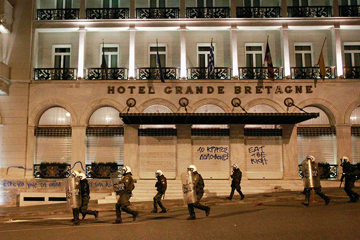 Greece unrest: Policemen run in front of the entrance of Grande Bretagne hotel 
