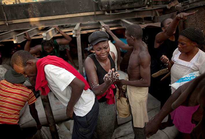 24 hours in pictures: People recover sacks containing rice from a crashed truck, Haiti