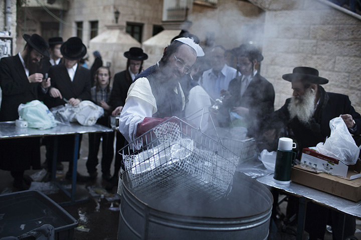 24 hours in pictures: An ultra-Orthodox Jewish man immerses cooking pots into boiling water