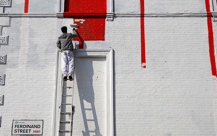 24 hours in pictures: A decorator paints the walls of a bar in Camden, London