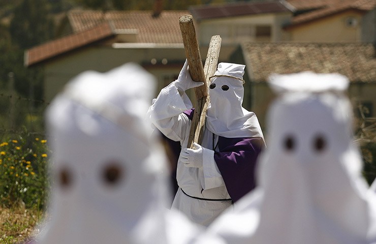 Good Friday traditions: Villarosa, Sicily: Penitents carry a cross during a Good Friday procession 