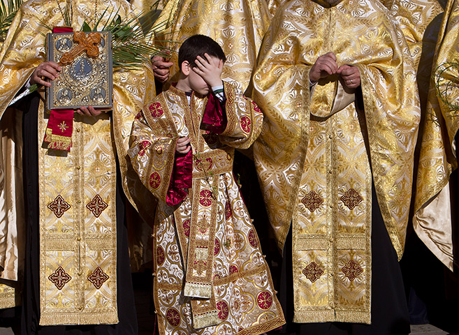 Easter Sunday: A boy covers his face during an orthodox Palm Sunday pilgrimage, Bucharest