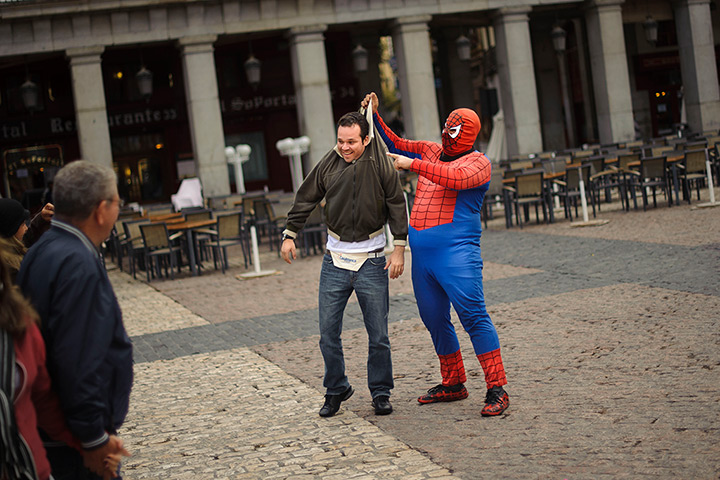 24 hours in pictures: A man dressed as  comic super-hero Spiderman performs with tourist, Madrid