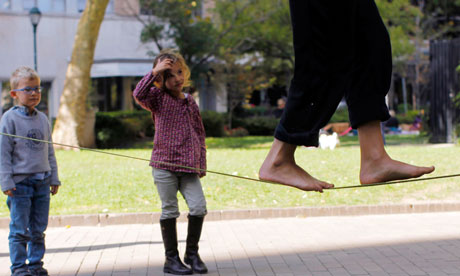 Children watch a woman walk on a tightrope 