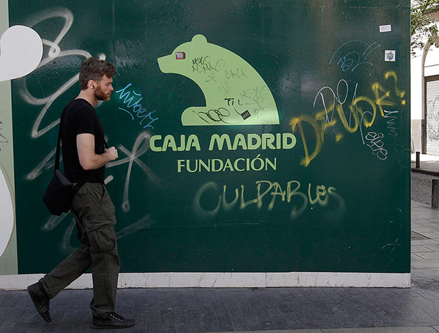 Biz week: A man walks past a Bankia Caja Madrid Foundation banner in central Madrid
