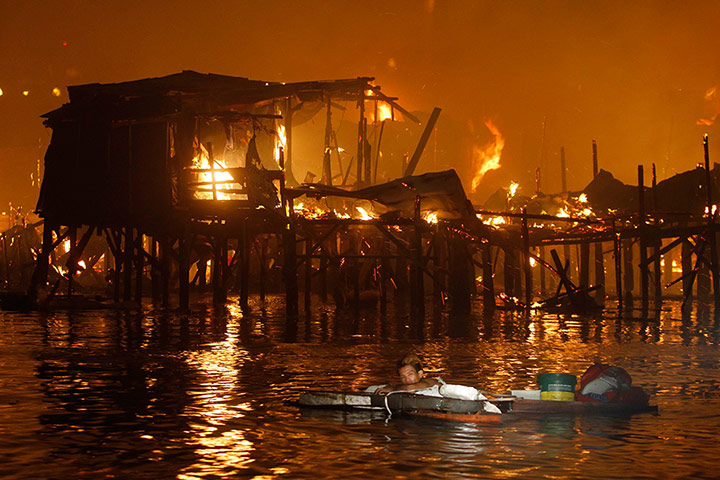 Manila: A resident holds on to his belongings while floating in Manila bay 