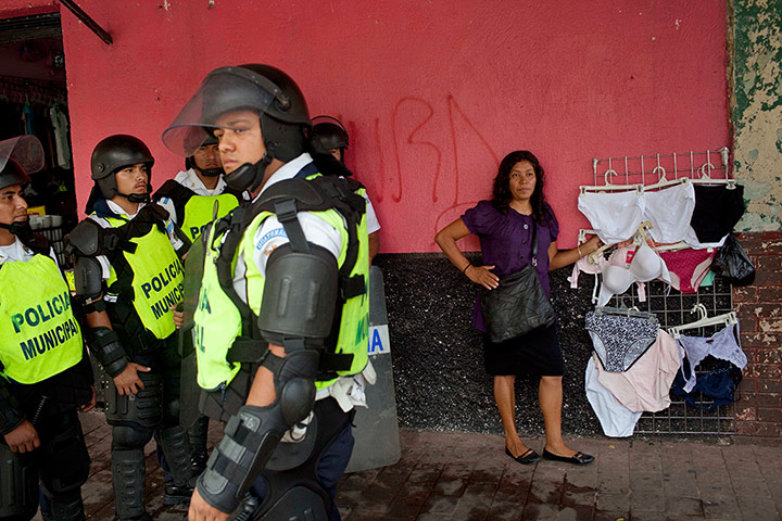 24 hours: A street vendor mans her stall as riot police stand guard