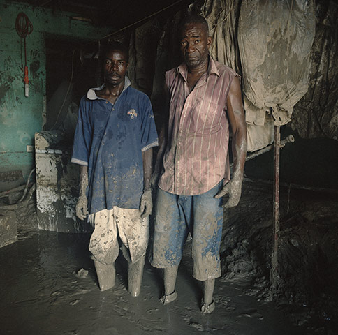 Drowning World: Workers Ledix Finep and Jeanvier Cassimer pause to as they clear the mud