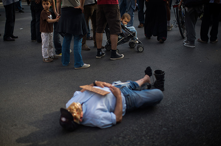 Spain protests: A child watches a demonstrator lying down on the ground in Barcelona