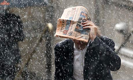A man tries to shelter under a copy of the Financial Times newspaper as he runs through a heavy rain
