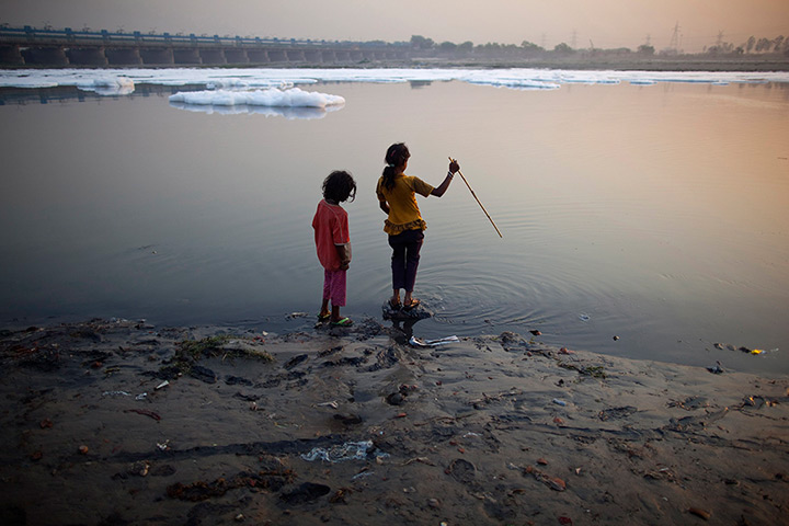 24 hours: New Delhi, India: Girls stand next to the waters of the river Yamuna