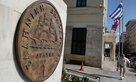 A man walks towards a replica of a drachma coin outside Athens town hall in Greece