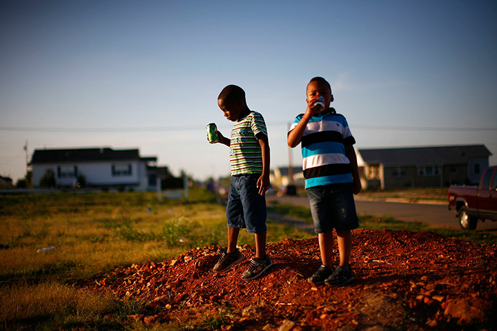 24 hours: Joplin, Missouri, US: Boys stand on an empty lot where a house once stood