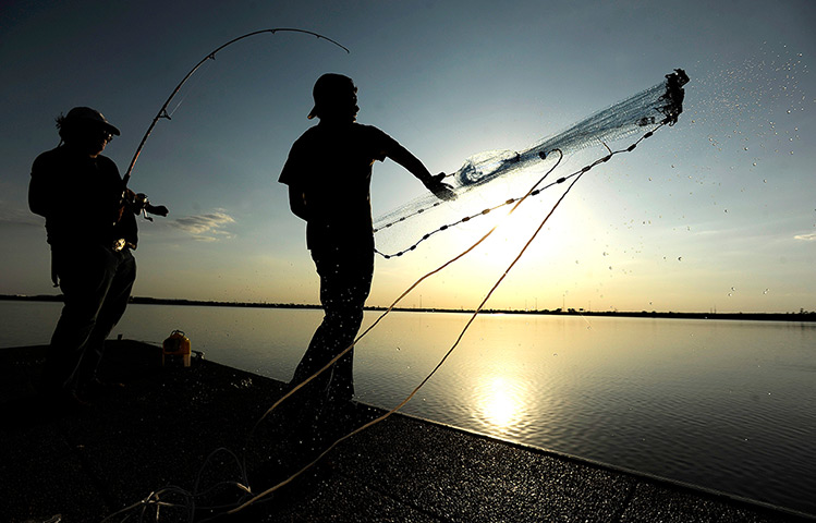 24 hours: Abilene, Texas, US: A man throws a net while fishing at Kirby Lake