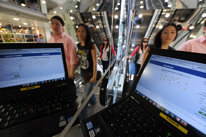 Week in business: Pedestrians walk past a computer showing facebook in Hong Kong