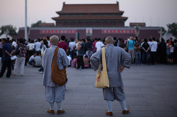 24 hours in pictures: Two monks wait before lowering flag at Tiananmen Square