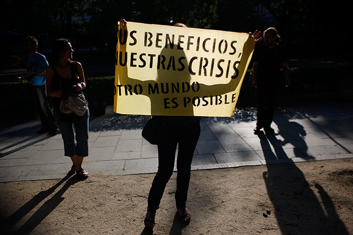 24 Hours: A woman holds a banner against capitalism in Madrid
