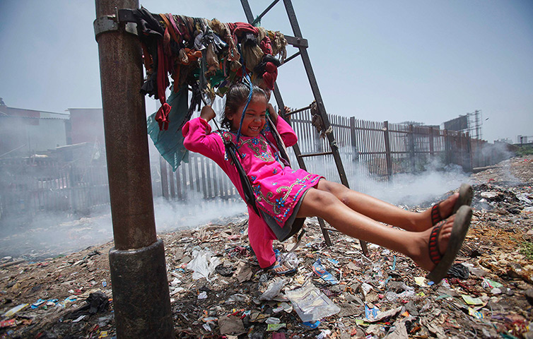 24 hours: Mumbai, India: A five-year-old girl plays on a cloth sling 