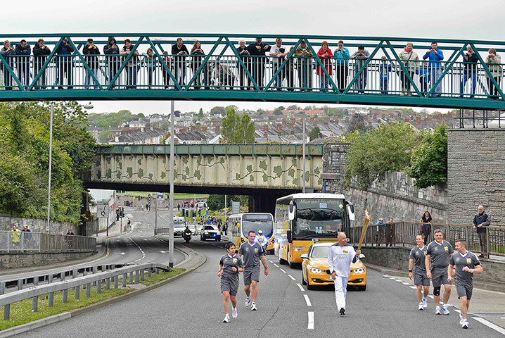Torch relay day 2: Spectators watch from a bridge as a torchbearer 004 runs through Plymouth