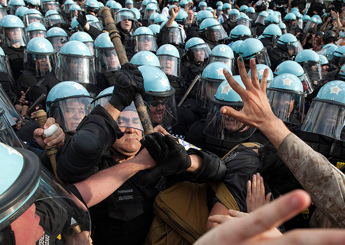 NATO summit protests: A police officer swings a baton at protesters