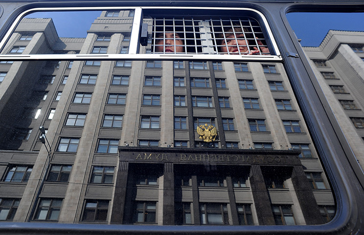 24 hours in pictures: Detained protesters look through a window of a police bus