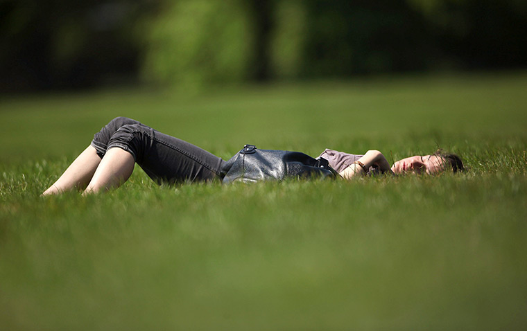 UK weather: A woman relaxes on the grass in Hyde Park