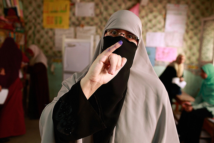 Egypt elections: A woman shows her ink-stained finger after casting her vote 