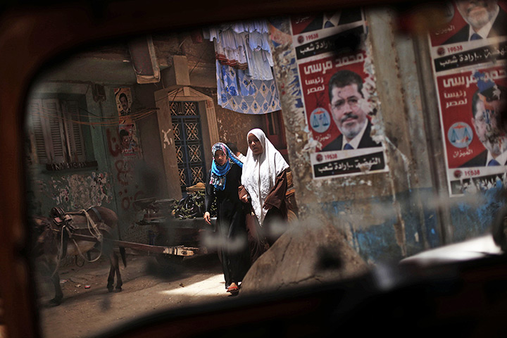 24 hours: Cairo, Egypt: Two Egyptian women walk past posters of Morsi